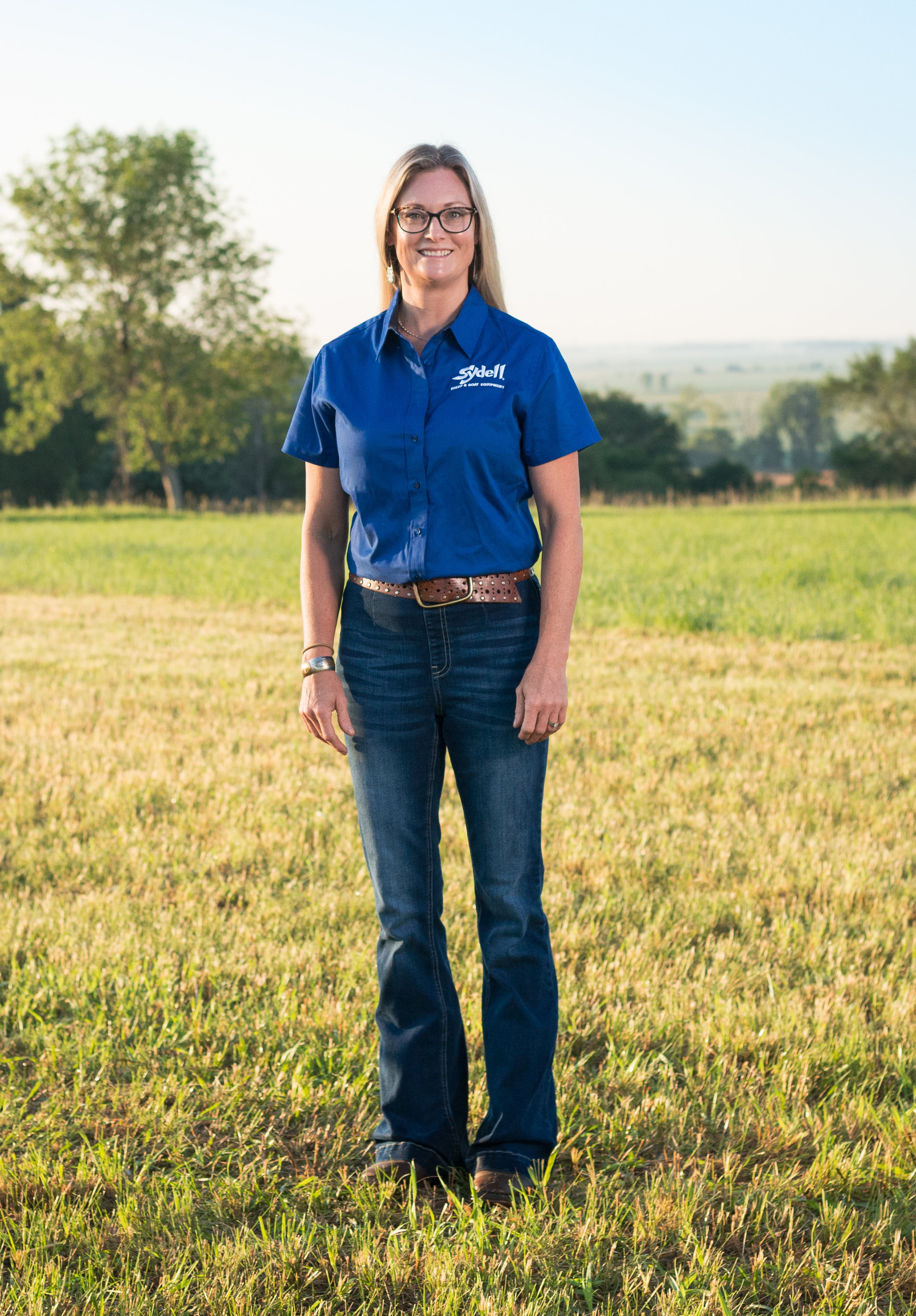 Person wearing a blue shirt with a Sydell logo standing in a field